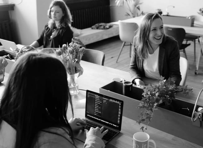 Three people on a desktop working with their laptops